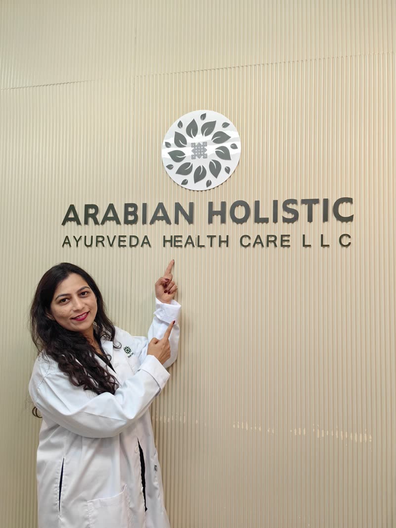 Dr. Seema Kamath of Arabian Holistic in a white coat, pointing to the centre logo